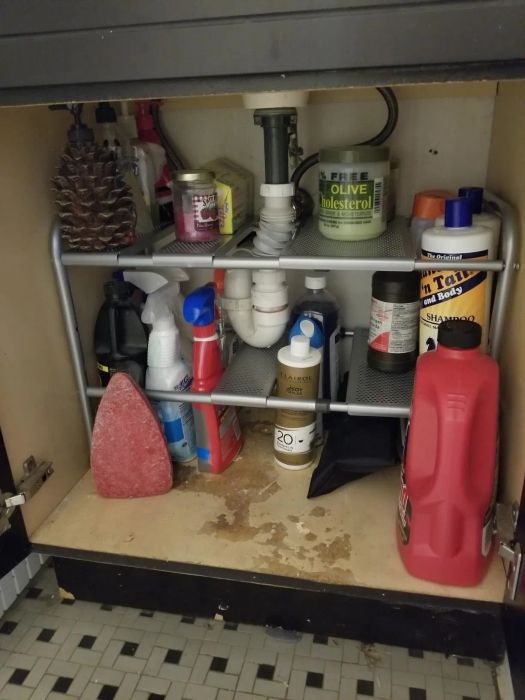photo of the same cabinet after installing a two-tier shelf, with cleaning supplies neatly arranged on the racks