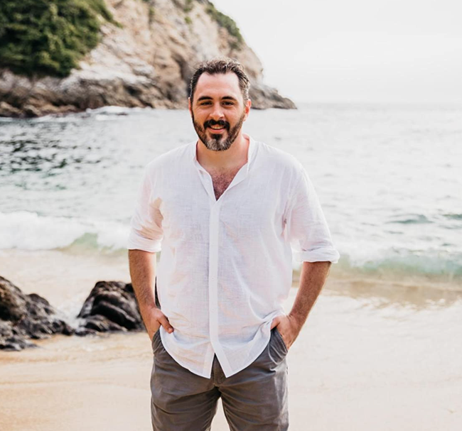 The reviewer is wearing a white linen button-down top paired with taupe-colored pants.