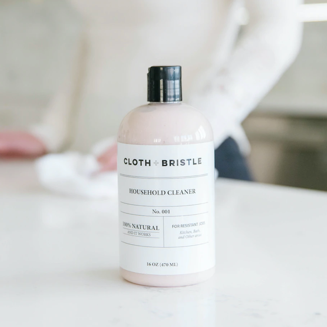 A pink cleaning solution bottle displayed while a model cleans a countertop