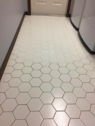 A bathroom floor with grout that is half white and half dirty gray.