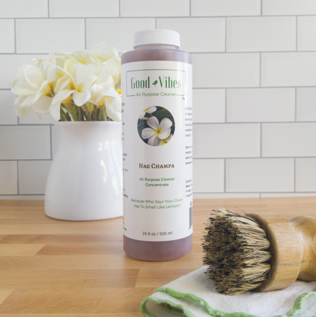 A bottle of Nag Champa placed in front of a white brick wall, accompanied by a scrub brush and cloth