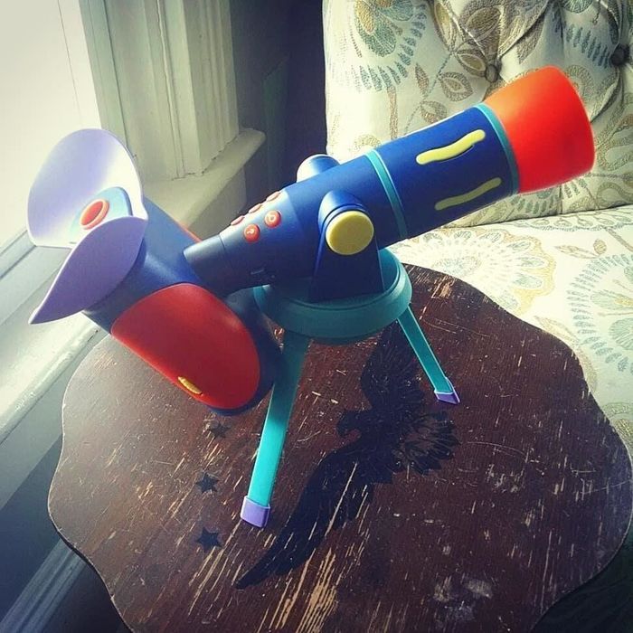 A reviewer's photo showing a blue plastic toy telescope, ready for stargazing adventures.