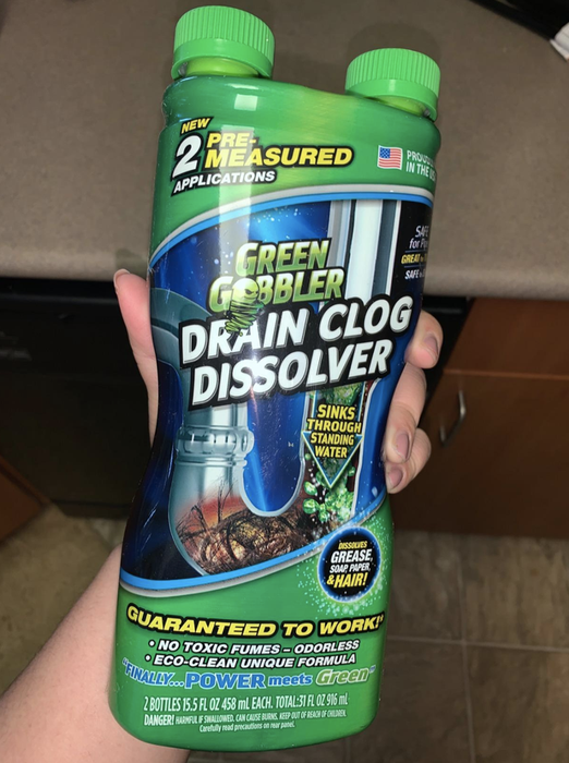 A reviewer demonstrates holding the Green Gobbler bottle, which has two twist-off caps at the top to prevent spills.