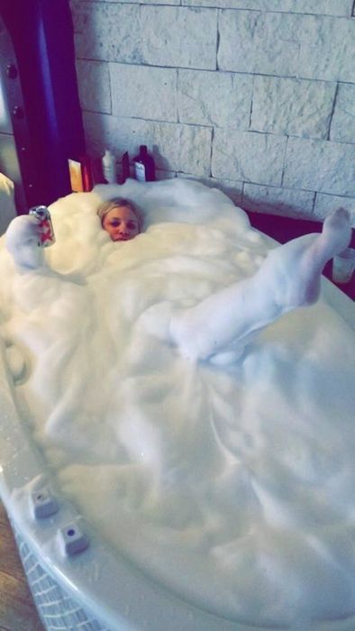 reviewer submerged in bubbles from neck to toe, enjoying a relaxing soak in a deep bath