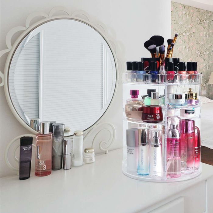 A makeup counter with a vertical, spinning acrylic makeup organizer.