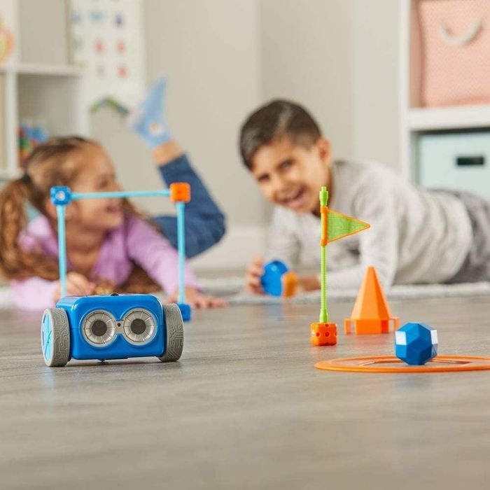 Two children playing with a blue robot on wheels, enjoying its movement.