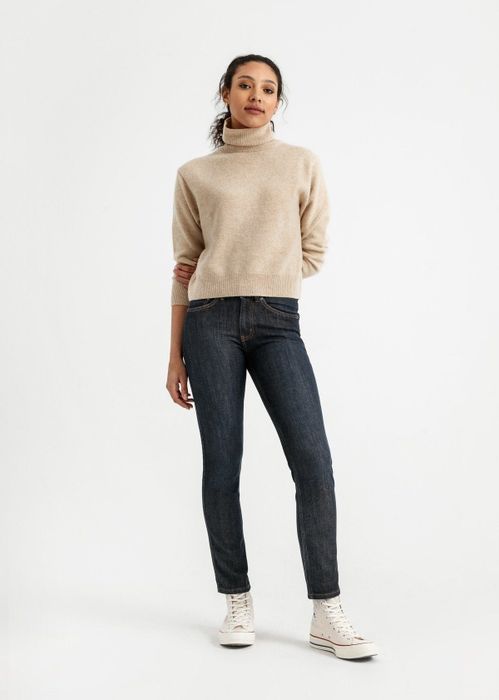 A model wearing mid-rise jeans paired with white Converse sneakers
