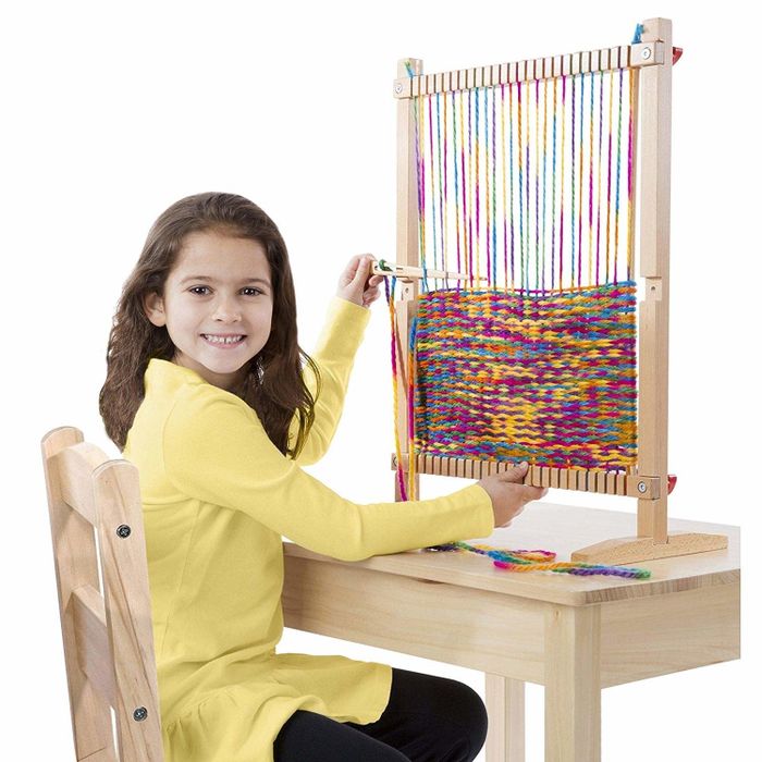 A model showing off the wooden loom on a desk, ready for weaving.