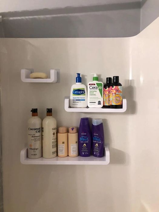 Photo of three shelves mounted on a shower wall, holding shampoo bottles and other bathroom essentials