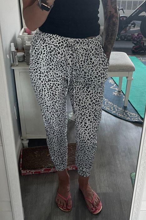 A reviewer styling the black and white leopard-print joggers.