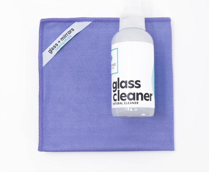 The glass cleaning kit featuring a clear bottle and a purple microfiber cloth.