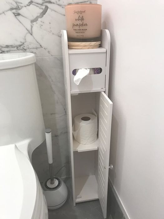 The white cabinet with the door open, revealing two spacious shelves inside.