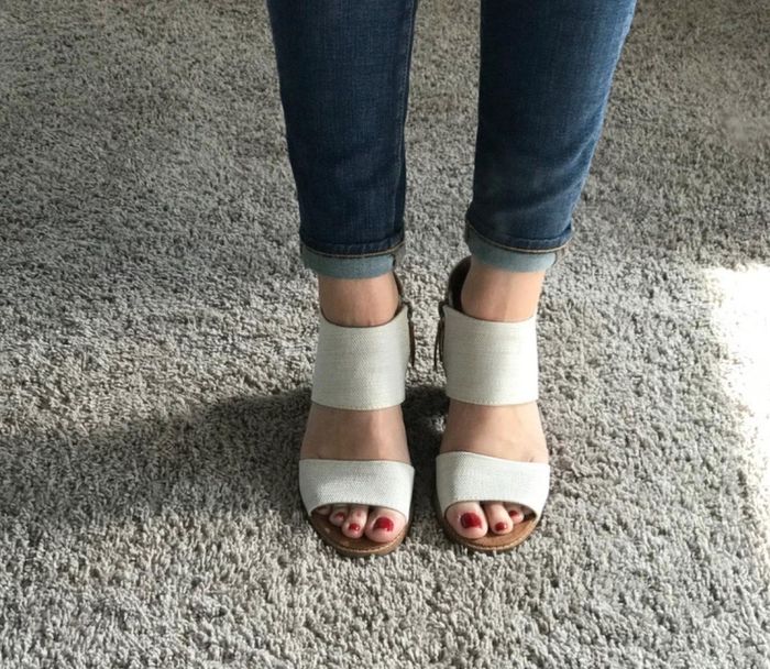 A front view of a reviewer confidently wearing white, thick-strapped sandals, showing off their chic and versatile style.
