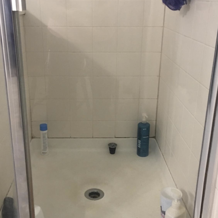 The reviewer's shower door after using the all-purpose power scrubber cleaning kit, now sparkling clear.