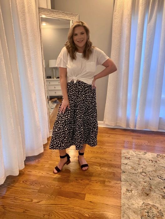 A reviewer pairing a black and white leopard print midi skirt with a simple white top, creating an effortlessly chic look.