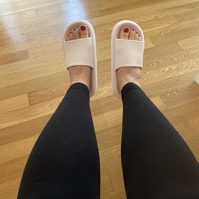 A reviewer sporting black leggings paired with a tan set of open-toed slippers.