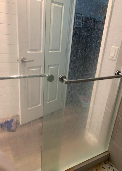 Reviewer's shower door shows water stains before using the hard water stain remover.