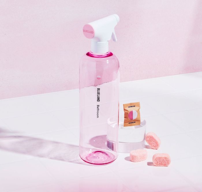 A pink and clear container of Blueland's Bathroom Starter Set with pink cleaning tablets.
