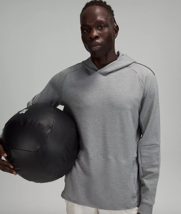 Model wearing a gray sweatshirt, holding a black workout ball