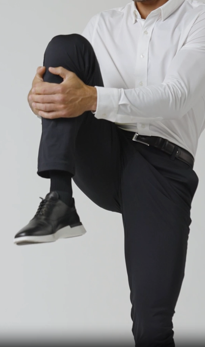 A man performing a stretch while wearing black pants