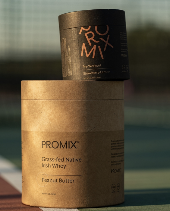 A close-up of a container of protein powder placed on a tennis court