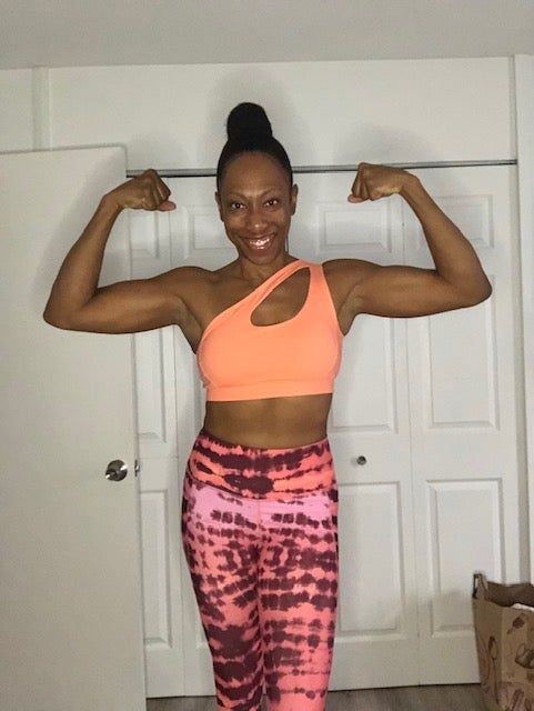 A reviewer rocking a coral one-shoulder sports bra and tie-dye leggings