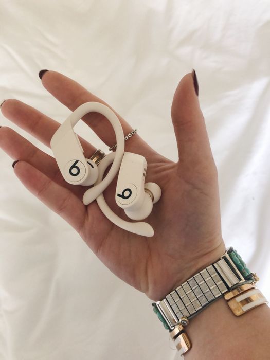 Emma is holding the same pair of compact headphones in her hands.