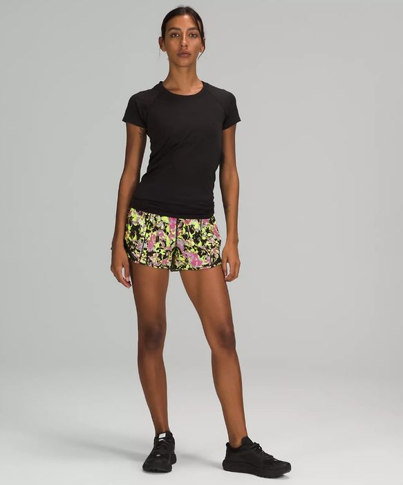 Model sporting neon yellow, black, and pink patterned running shorts paired with a black tee