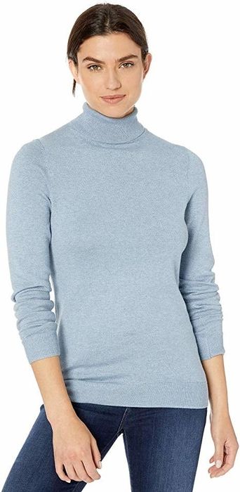 A model is shown wearing a light blue turtleneck sweater.