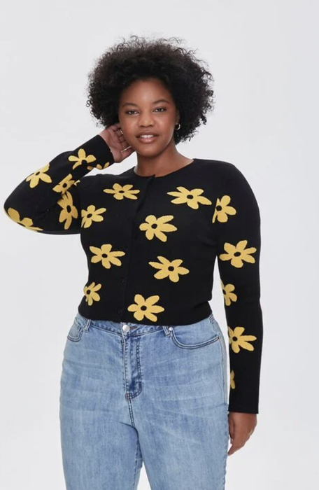 A model stuns in a black cardigan featuring vibrant yellow daisies, bringing a burst of color to a classic style.