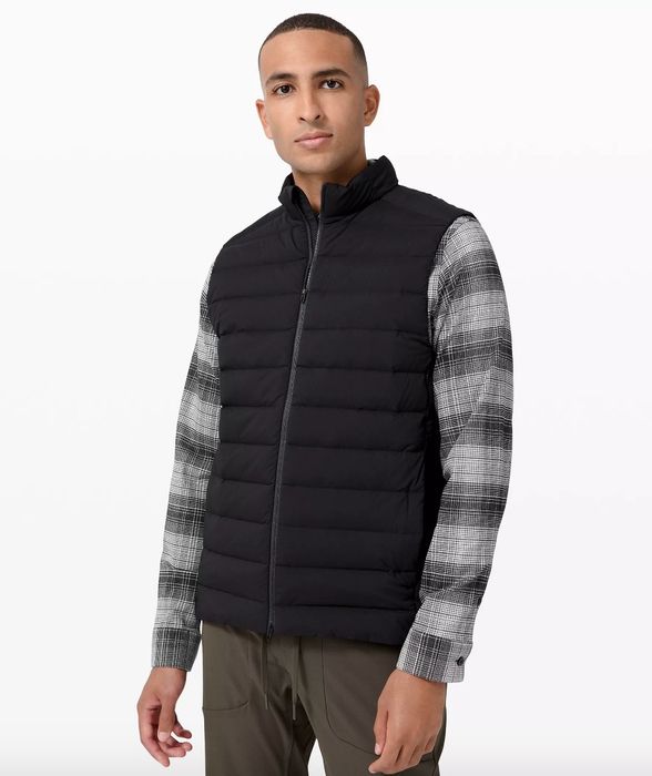A model wearing a black vest over a flannel shirt