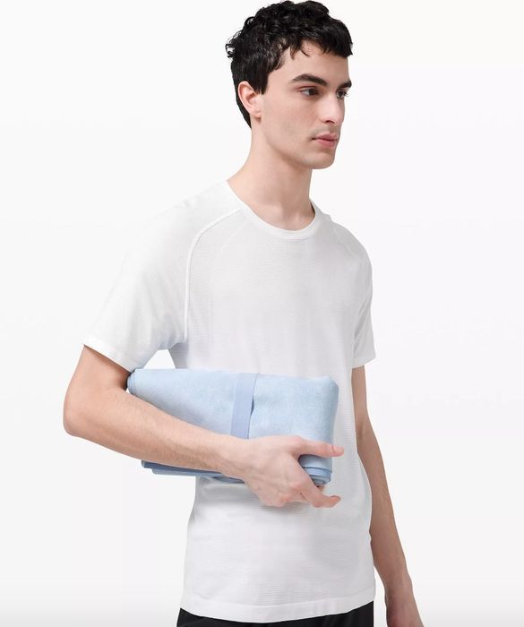 A model holding a light blue travel yoga mat