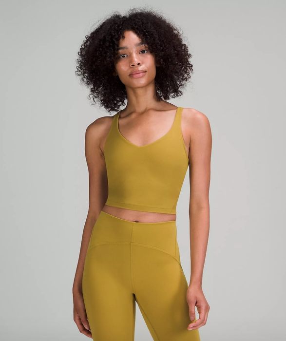 A model wearing a mustard-colored tank paired with matching leggings