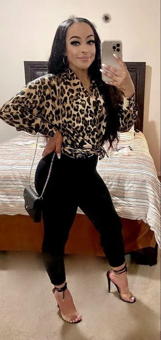 A reviewer rocking the same high-shine leggings in black, paired with a dressy leopard blouse and heels