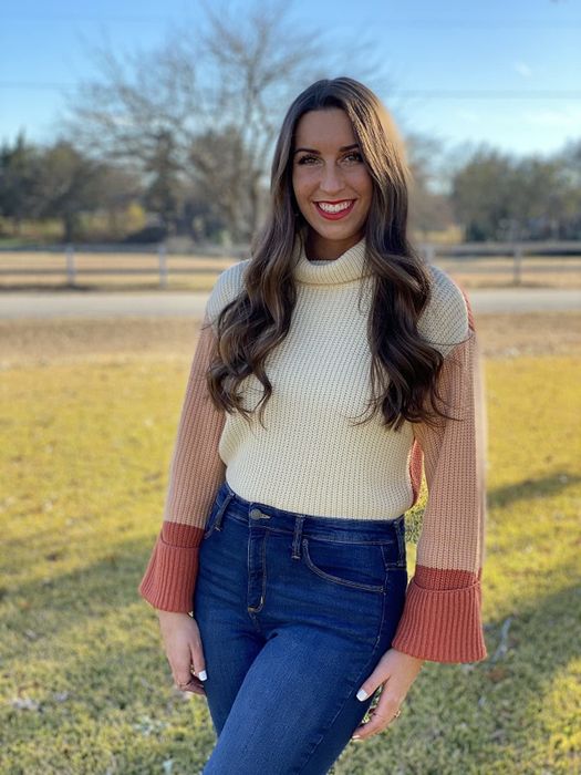 a reviewer wearing the sweater in a white and orange color-block design