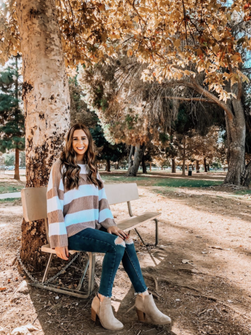A reviewer sporting a white and brown vertical striped sweater.