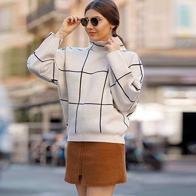 a model in the white pullover featuring a subtle black grid design