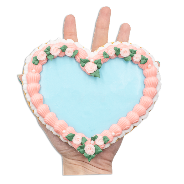 A heart-shaped cookie featuring pink piping around the edges with a blue frosting center