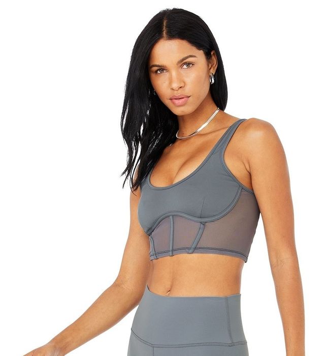 The model is sporting a grey mesh corset sports bra with visible boning for structure and style