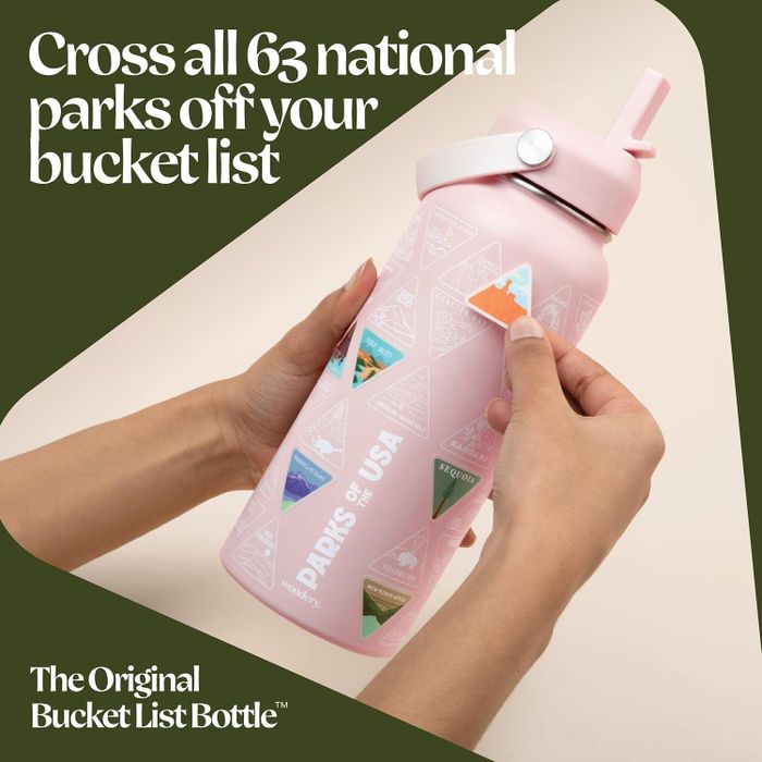 A person adding a park sticker to a pink water bottle