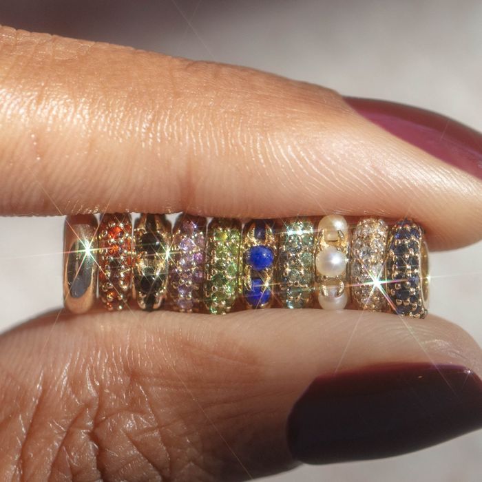 A hand showcases a collection of sparkling gemstone rings, each featuring unique designs and stones, offering a wide selection of jewelry options ideal for shopping.
