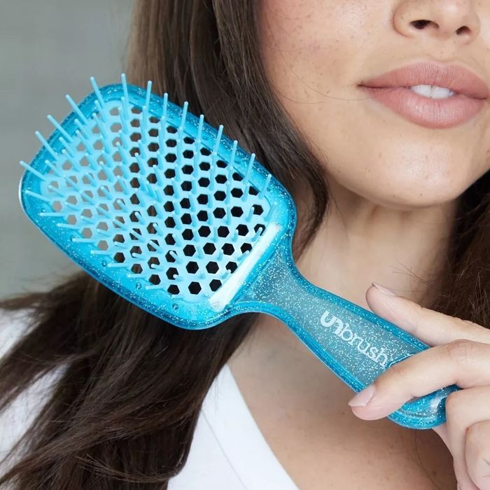 A woman is holding a blue hairbrush.