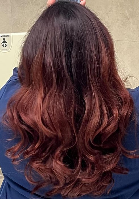 Image of a reviewer with rich burgundy curly hair.