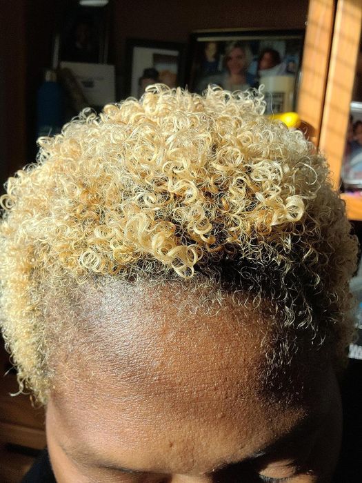 A close-up shot of a reviewer showcasing their shiny, short blonde coils.