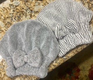 A photograph showing two soft, absorbent hair towels resting on a smooth granite surface.