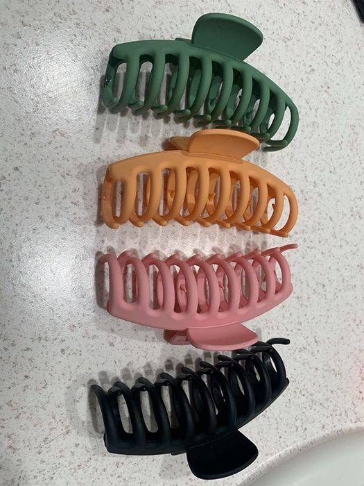 A reviewer's collection of colorful hair claw clips arranged in a row