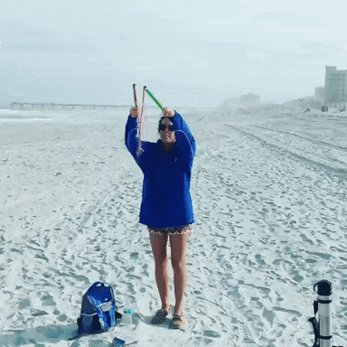 A reviewer using the bubble wand to create huge bubbles on the beach