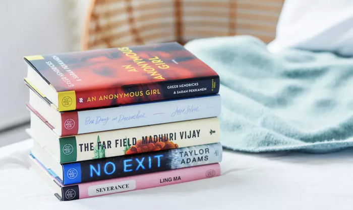 A collection of various books arranged on a white surface beside a striped cushion.