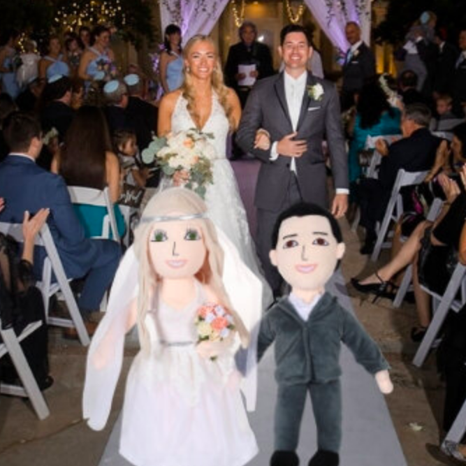 A couple in wedding attire with matching dolls dressed the same way.