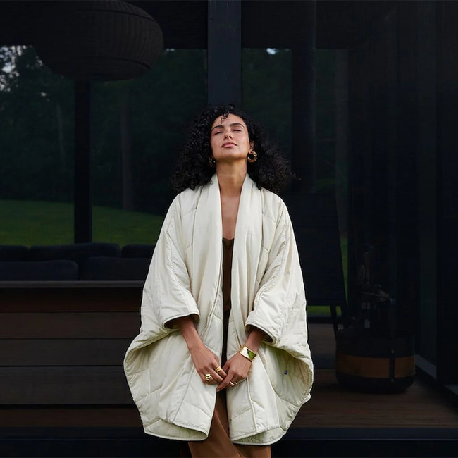 a model wearing the housecoat outdoors, accessorized with a full outfit underneath